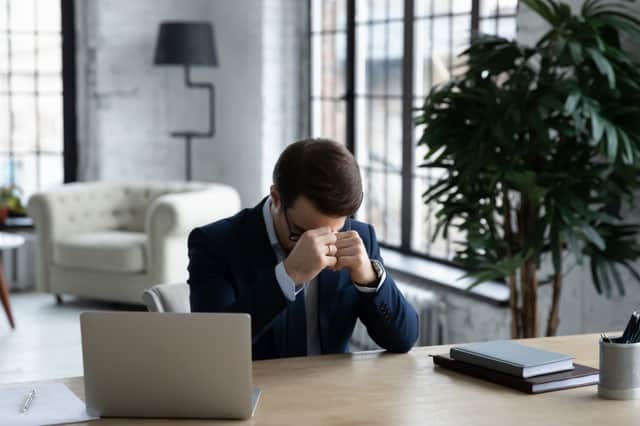 Stressed young male executive ceo manager sitting at table with head down, depressed by company bankruptcy, worrying of wrong business decision, feeling nervous alone in office, burnout concept.