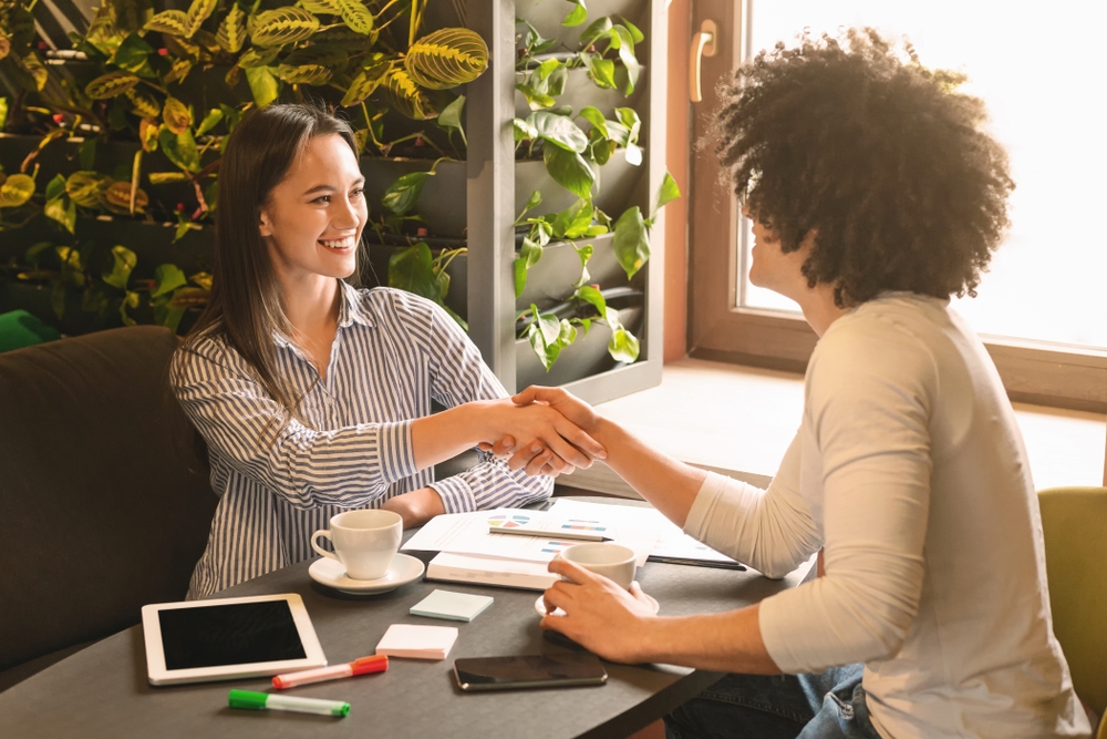 New partnership. Friendly businesspeople reached agreement, handshaking during business lunch in cafe