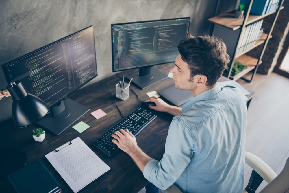 Top above high angle view portrait of his he nice attractive focused skilled geek guy typing bug track report cyberspace security at modern industrial interior style concrete wall work place station