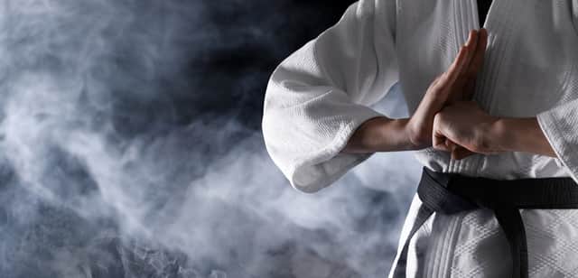 Karate fighter in smoke on black background, closeup. Banner design with space for text