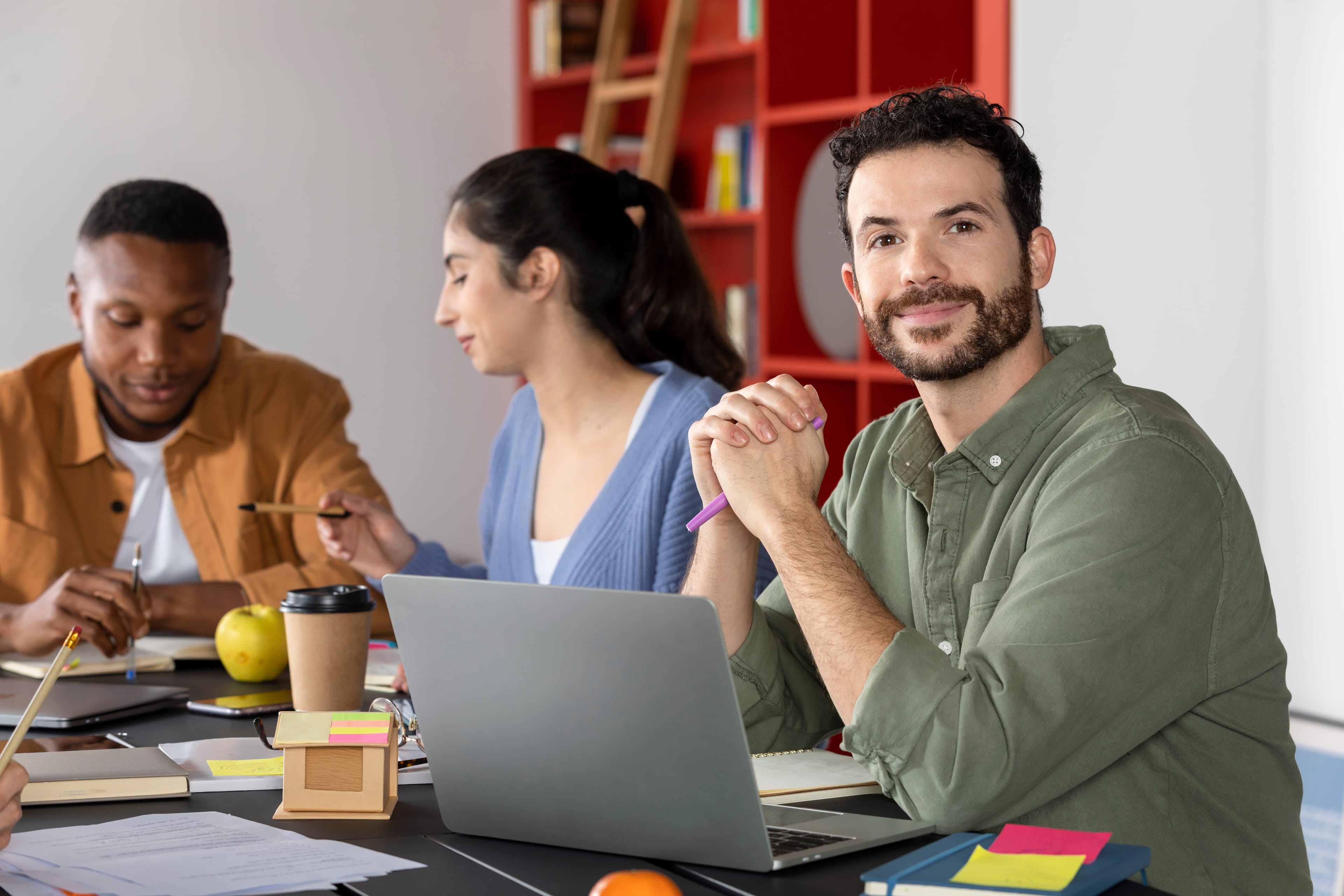 Profissionais em momento de atualização profissional, reunidos em ambiente de estudo e trabalho com notebook, cadernos e materiais de apoio.